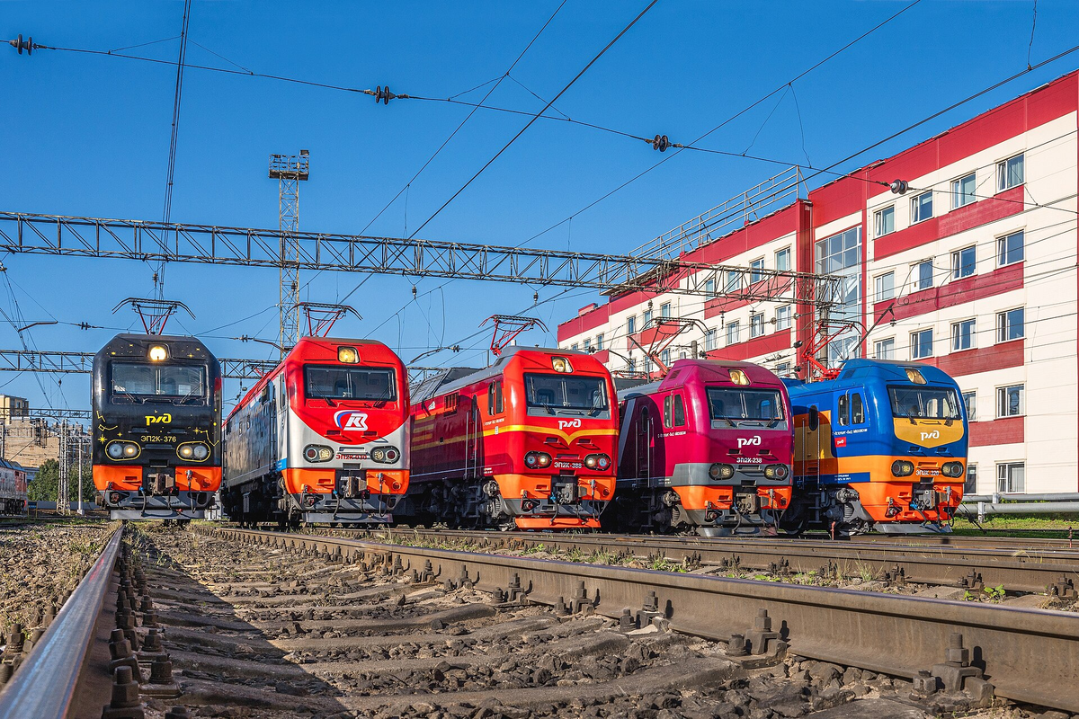 Электровозы ЭП2К в различных вариантах окраски. Слева направо: чёрный 376 «Ночной экспресс», классический красно-белый 030, красный 388 «Красная стрела», малиново-белый 238 «Гранд экспресс» и сине-оранжево-жёлтый 320 «Мегаполис». Источник фото: ru.wikipedia.org Авторство: Ulan3. RailGallery (photo), CC BY 3.0, https://commons.wikimedia.org/w/index.php?curid=155908914
