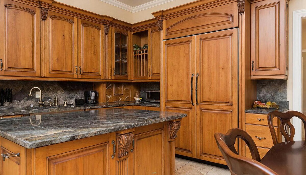 Классическая кухня с фасадами из массива ореха, резными филёнками и латунными ручками. Гранитная столешница, уютная атмосфера.