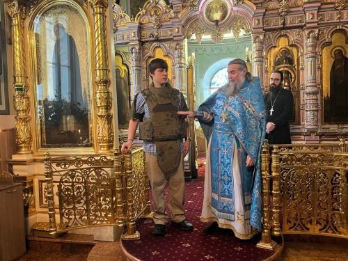 Протоиерей Виталий Кулешов демоснстрирует прихожанам бронежилет на алтарнке Германе