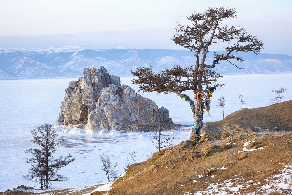    Скала Шаманка на острове Ольхон зимой, окруженная прозрачным льдом озера Байкал. / Фото: iStock