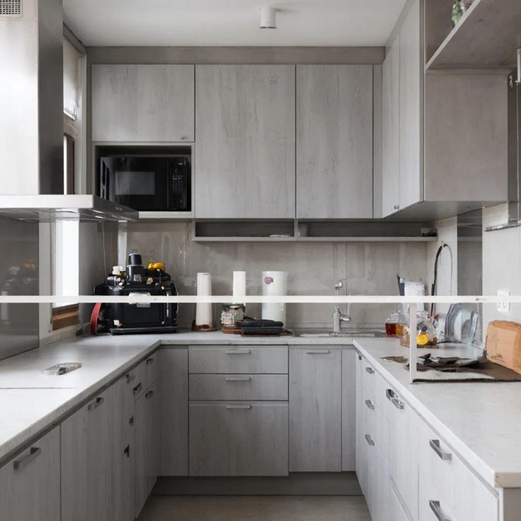 Современная минималистичная кухня с матовыми светло-серыми фасадами и белой столешницей из искусственного камня.