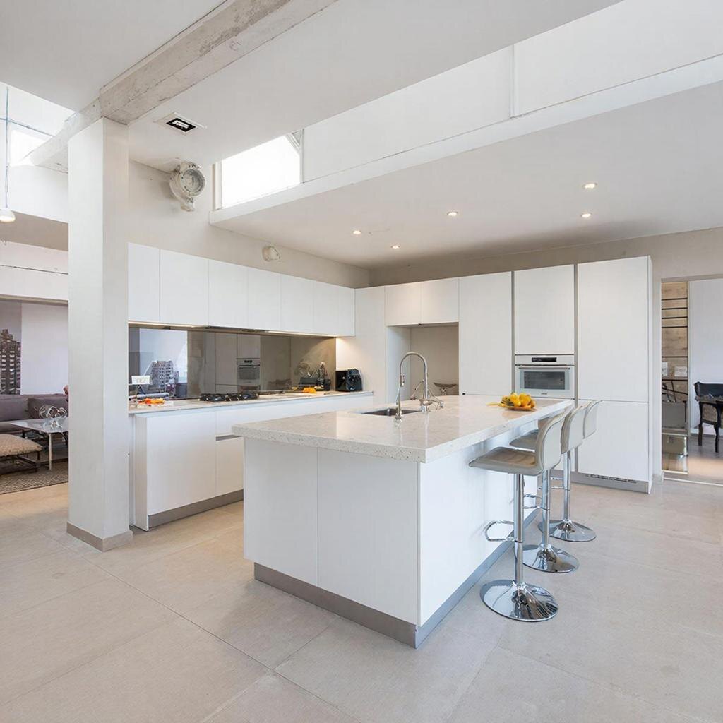 Просторная кухня-гостиная с большим островом, барной стойкой и высокими стульями.