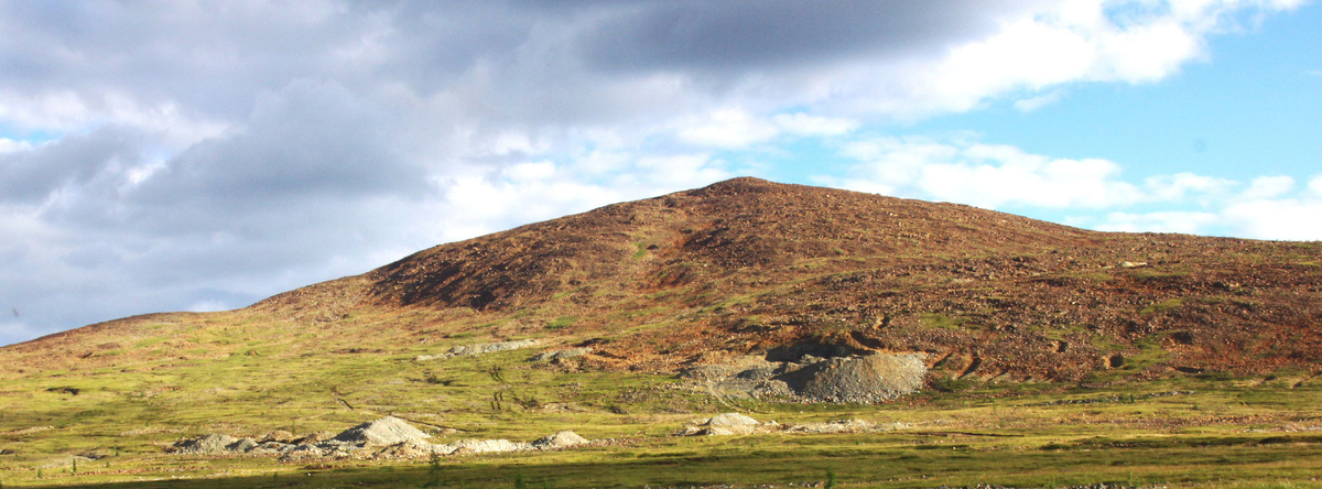 Фото 1. Гора Хара-Нурай (пер. с бурятского – Черное озеро) – официальное название, закрепленное на картах или Улан-Хода (пер. с бурятского - Красная гора) - исторически сложившееся, абсолютная высота 2507,3 м. Вид с севера на юг. На склоне хорошо видны отвал штольни и канавы вскрывавшие жилы нефрита. Съёмка 2015 года