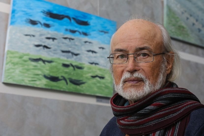 Геннадий Райшев на фоне своей картины. Источник: просторы интернета