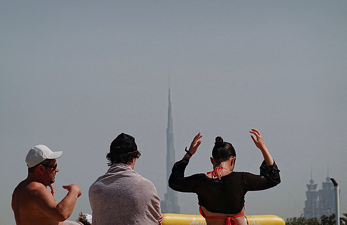    Люди на пляже на фоне небоскреба Бурдж-Халифа после иранской атаки. Дубай, 1 марта 2026 года. REUTERS/Amr Alfiky