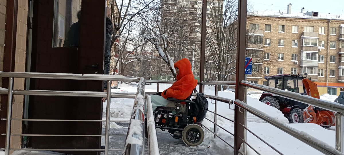 Администратор придерживает дверь, чтобы гость на инвалидной кресло-коляске мог войти в помещение
