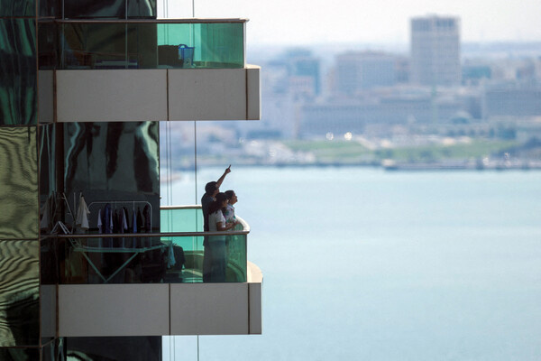 Люди наблюдают за взрывами со своих балконов в Дохе, Катар, 28 февраля 2026 года / Mohammed Salem/Reuters   📷