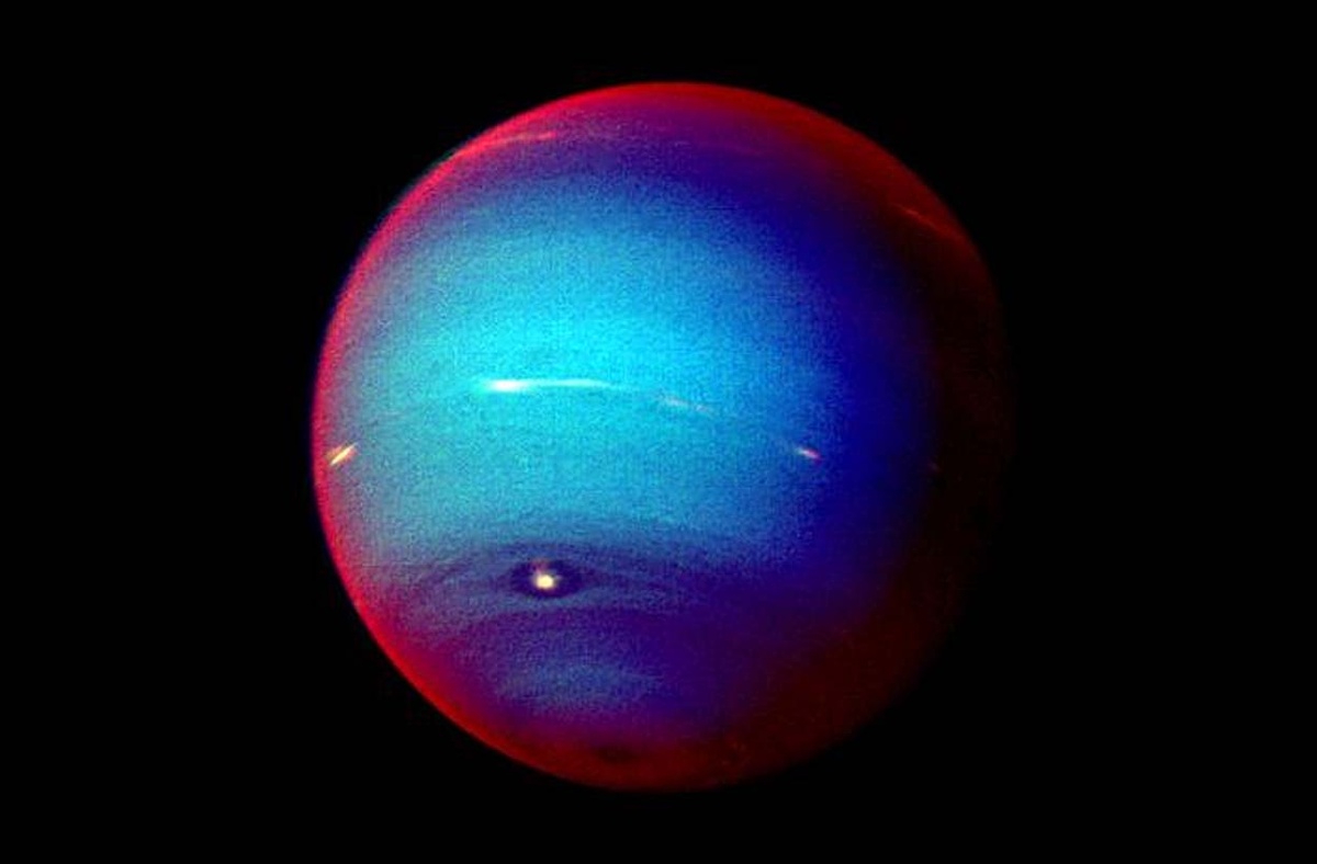 Составное изображение Нептуна в ложных цветах, "сшитое" из снимков "Вояджера-2", полученных через три фильтра. Белые и ярко-красные области показывают солнечный свет, отраженный до прохождения через слои метана; красная кайма по краю диска возникает из-за рассеяния в верхней дымке. В центре свет проходит глубже и сильнее поглощается метаном — поэтому оттенок кажется сине-голубым / © NASA/JPL