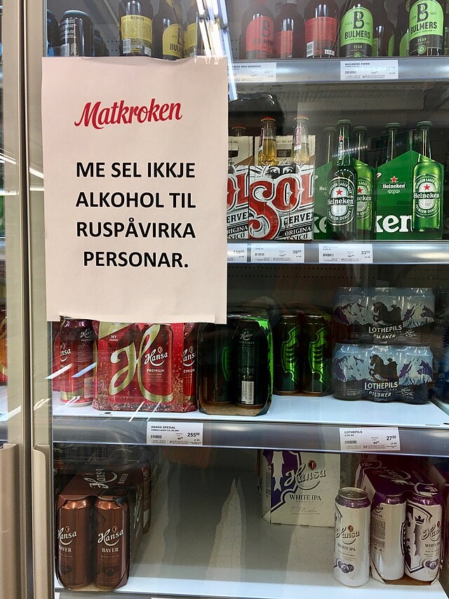 Wolfmann. Холодильник со стеклянной дверцей. Вывеска на норвежском языке: " Мы не продаем алкоголь лицам, находящимся в состоянии алкогольного опьянения". В городе Лейрвик на острове Сторд, Норвегия. 2018-03-10