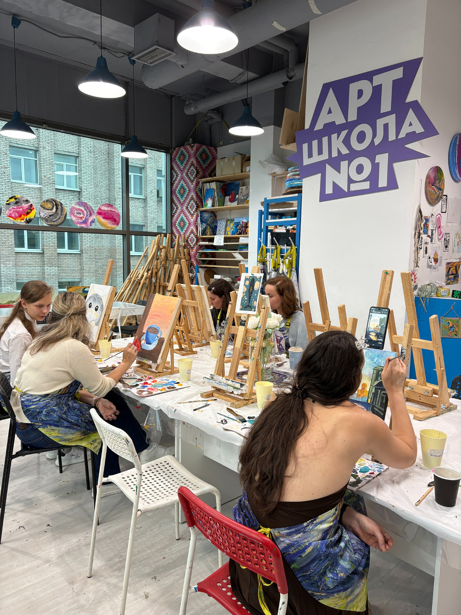 Я была в филиале на Лиговском проспекте. Школа занимает 1 не большую комнату, в ней: ресепшен, стойка для одежды, стол с чаем/кофе, раковина, три стола. Тут и там мольберты, картины, полочки, но они удивительным образом не захламляют пространство.