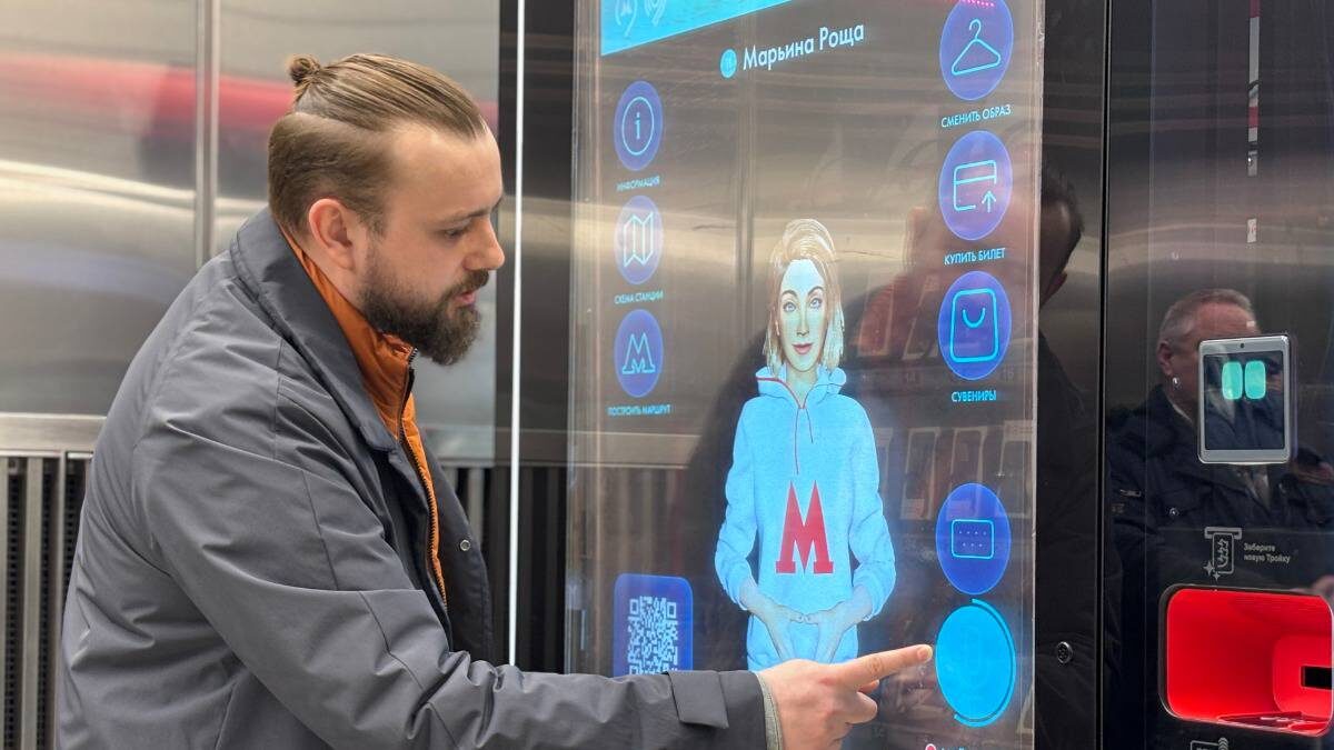    Начальник навигационно-информационного комплекса метро Сергей Литвинович демонстрирует работу и возможности Александры на цифровой стойке общения на станции «Марьина Роща» / Фото: Василиса Чернявская / Вечерняя Москва