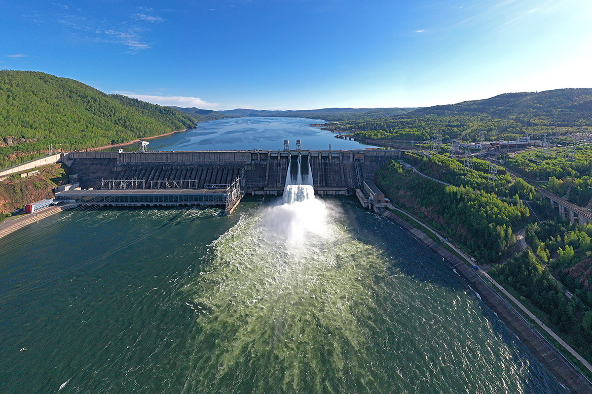     Плотина Красноярской ГЭС – длиной 1072 и высотой 128 метров. Систему шлюзов для ее преодоления пришлось бы делать тоже огромной и дорогостоящей. Поэтому решили использовать судоподъемник (в правой стороне кадра видны его эстакада и, на самом верху, судовозная камера)