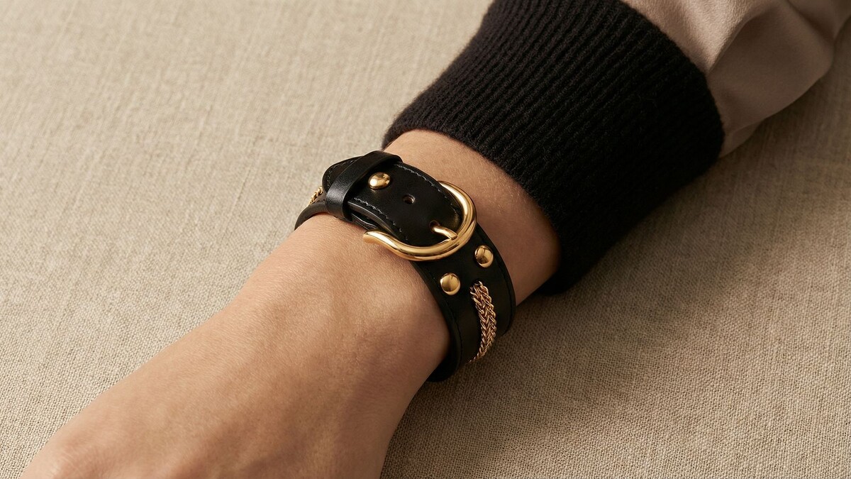 Элегантный черный кожаный браслет с массивной золотой пряжкой и вплетенной золотой цепочкой — идеальный баланс строгости и роскоши.