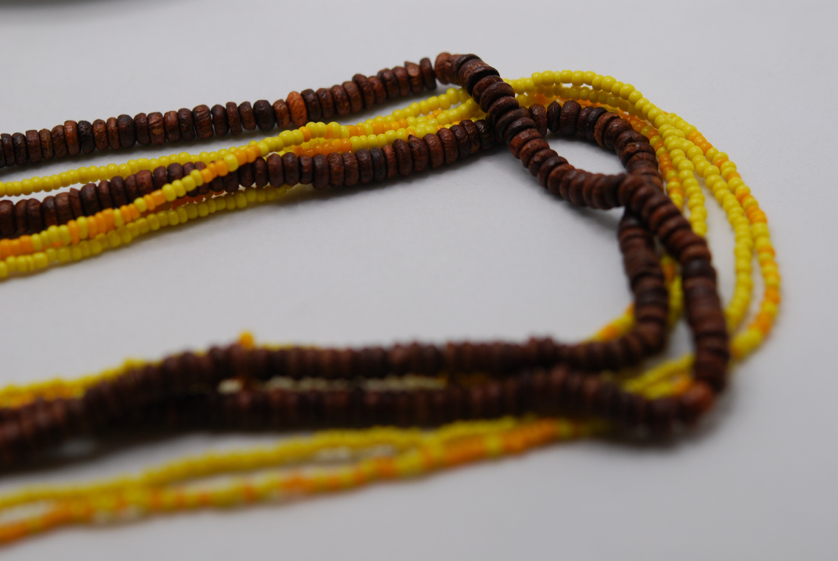 Коричневая нить из мелких бусин и желтые нити из бисера.