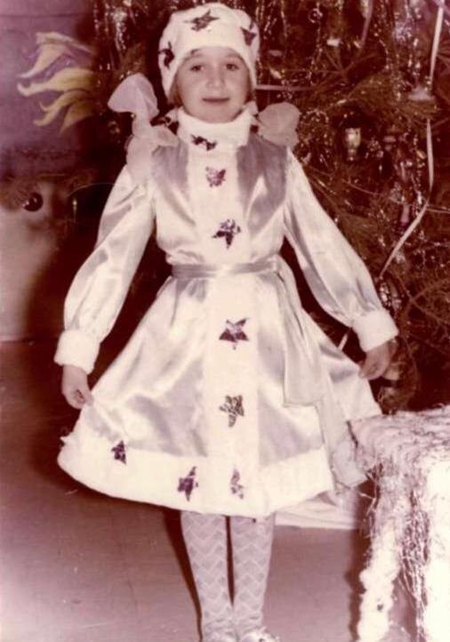 Мне шесть лет и на мне "шубка" из атласа, подбитая ватным "мехом". Чтобы "мех" держался на месте, мама простегала вату между слоями марли. Звезды ‒ из разноцветной фольги, из которой в те времена делали крышки для бутылок (как-никак, мама работала на молокозаводе). Сказочный образ завершали импортные гольфы в тон и чешки, обтянутые тем же атласом. В полной мере оценить роскошь этого костюма могут только те, кто рос в СССР 😁