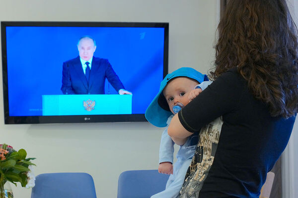 Девушка с ребенком на руках смотрит трансляцию послания президента РФ Федеральному Собранию, 21 апреля 2021 года / Сергей Пятаков/РИА «Новости»   📷
