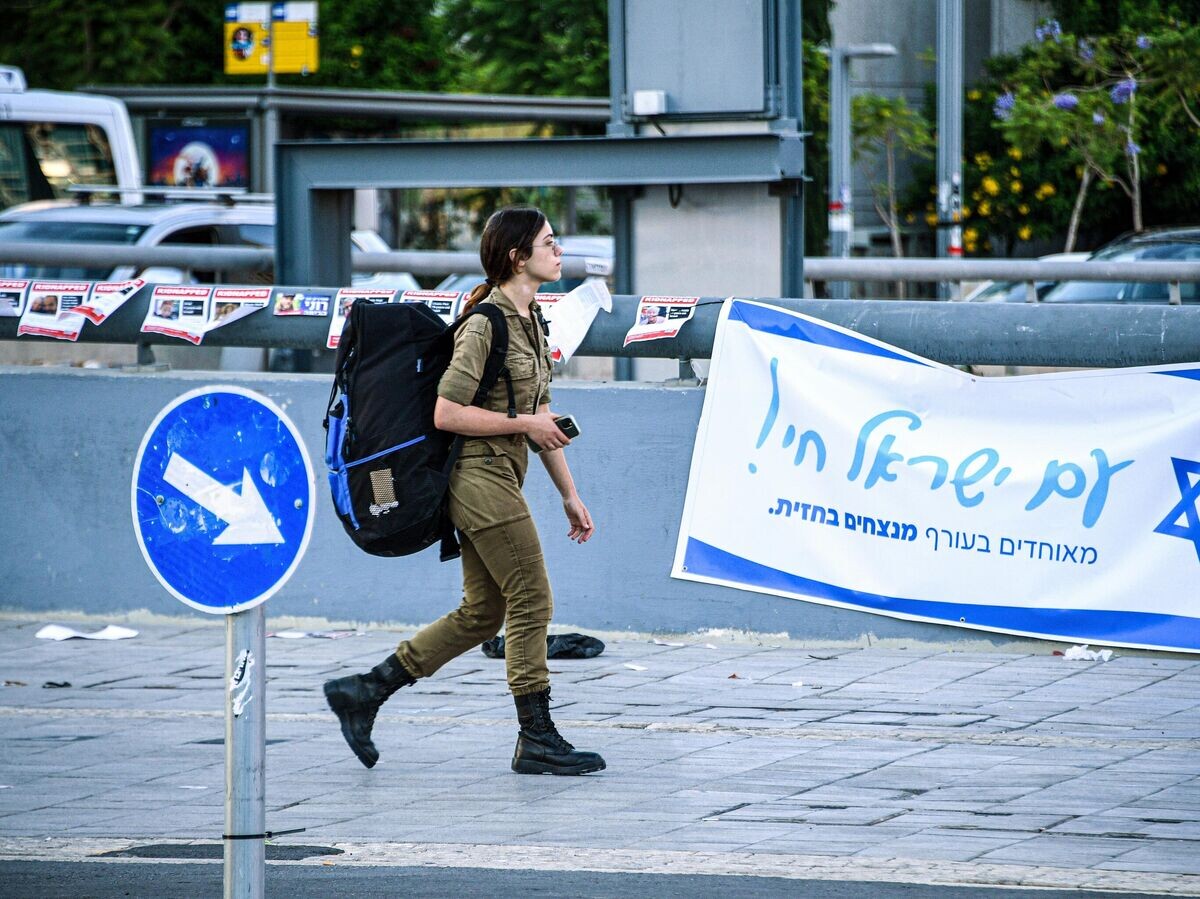    Военнослужащая армии обороны Израиля на фоне патриотической агитации в Тель-Авиве | © РИА Новости / Стрингер