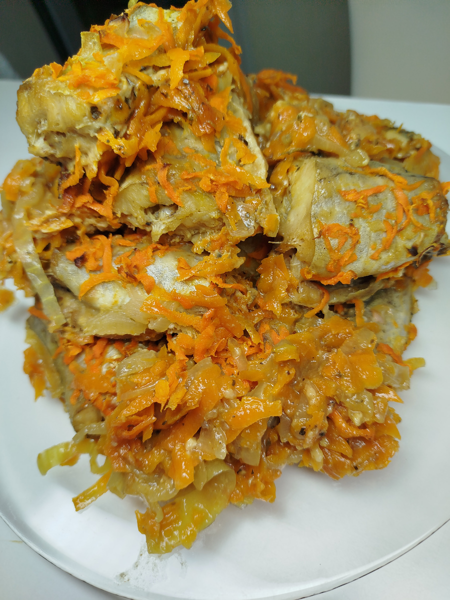 Промываем размороженную рыбу, ножницами отрезаем плавники и хвост. Удаляем чёрную плёночку.Разрезаем на части. Укладываем куски а обычный пакетик и солим, перчим, добавляем приправу для рыбы и растительное масло. Завязываем пакет и трясём , чтобы снять м масло хорошо распределились по рыбе. Добавляем муку и снова трясём в пакете.
А отдельной миске смешиваем майонез+ соевый соус+ дижонская горчица. Добавляем соус в пакет и снова хорошо трясём. Оставляем на 20 минут.
Нарезаем полукольцами лук и выкладываем его на противень, равномерно. Нарезаем морковь и тоже выкладываем равномерно. Нарезаем чеснок, добавляем и перчим, солим , молотый кориандр, приправа для овощей
Перемешиваем всё. Половину оставляем на дне протвиня. Укладываем сверху куски рыбы, и вторую половинку моркови с луком посыпаем сверху на рыбу. Сверху протвинь закрываем намоченным в воде пергаментом.
В духовку 200 градусов на 45 минут.
Когда рыбка приготовится, вынуть кусочки  рыбы отдельно на тарелку . Сварить рис и положить в протвинь к овощам, перемешать, и подавать как гарнир к рыбе.