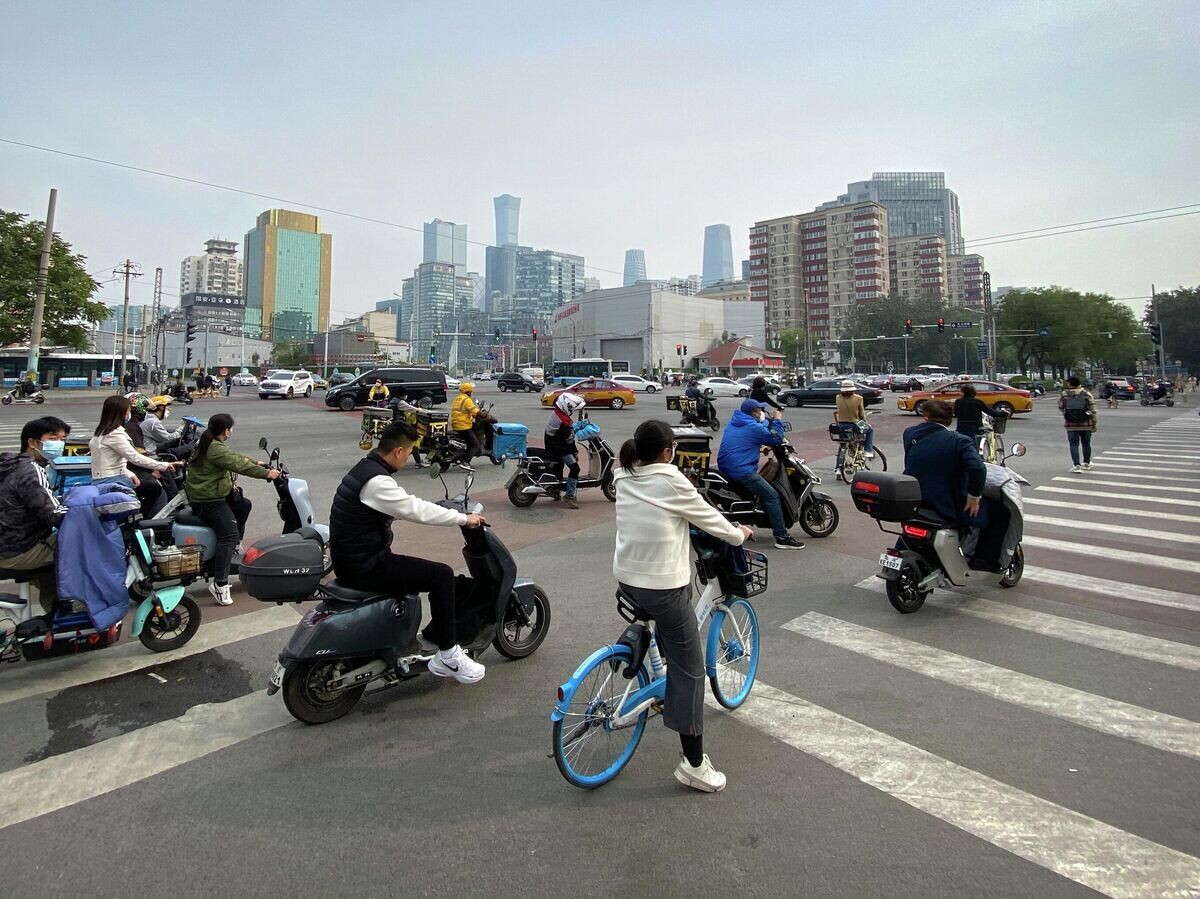    Люди на скутерах и велосипедах в центральном деловом районе Пекина | © AP Photo / Mark Schiefelbein