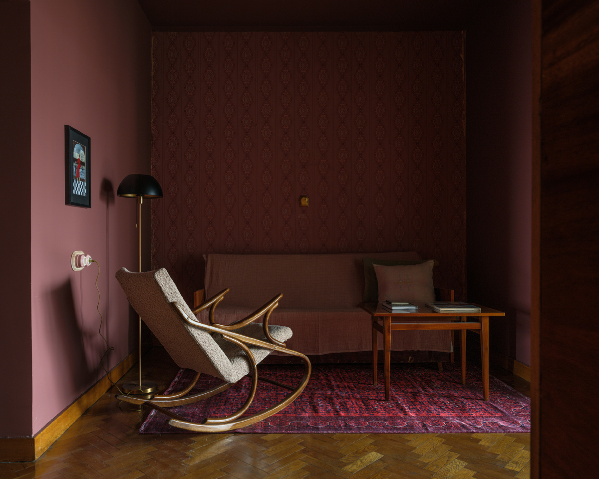В холле винтажные диван, столик и кресло-качалка, а фоном им служит стена со старыми обоями.
