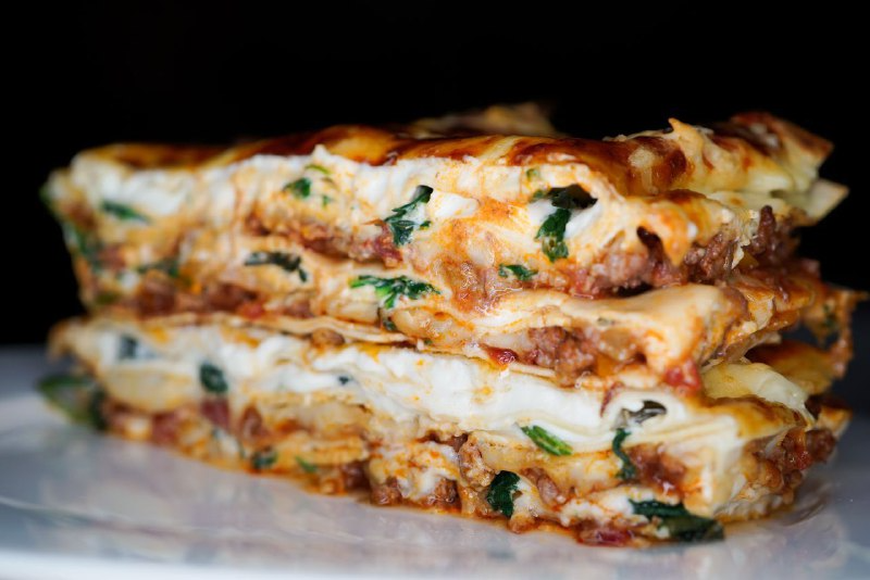 Ингредиенты:
• говяжий фарш 
• сыр моцарелла 
• сыр пармезан 
• шпинат 
• зелёный базилик 
• репчатый лук 
• сельдерей 
• красное вино 
• соус болоньезе 
• соус бешамель