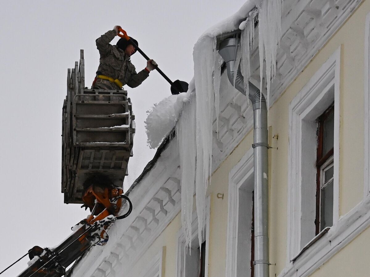    Сотрудник коммунальной службы счищает снег с крыши дома в Посланниковом переулке в Москве | © РИА Новости / Евгений Одиноков