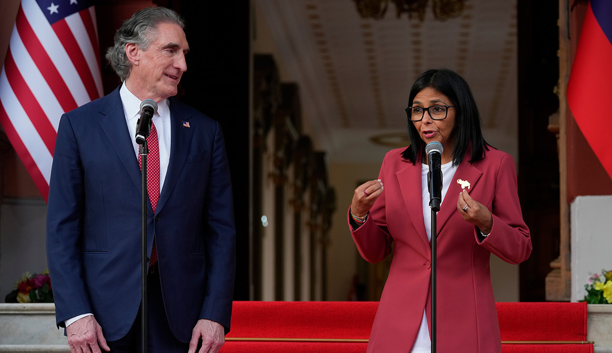   Ariana Cubillos / AP- Делси Родригес выступает с совместным заявлением с министром внутренних дел США Дугом Бургумом