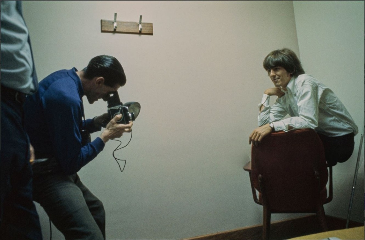 Английский фотограф Гарри Гудвин делает портретный снимок гитариста Джорджа Харрисона в гримерной за кулисами в Лондоне, примерно в 1965 году. Фото Рона Ховарда.