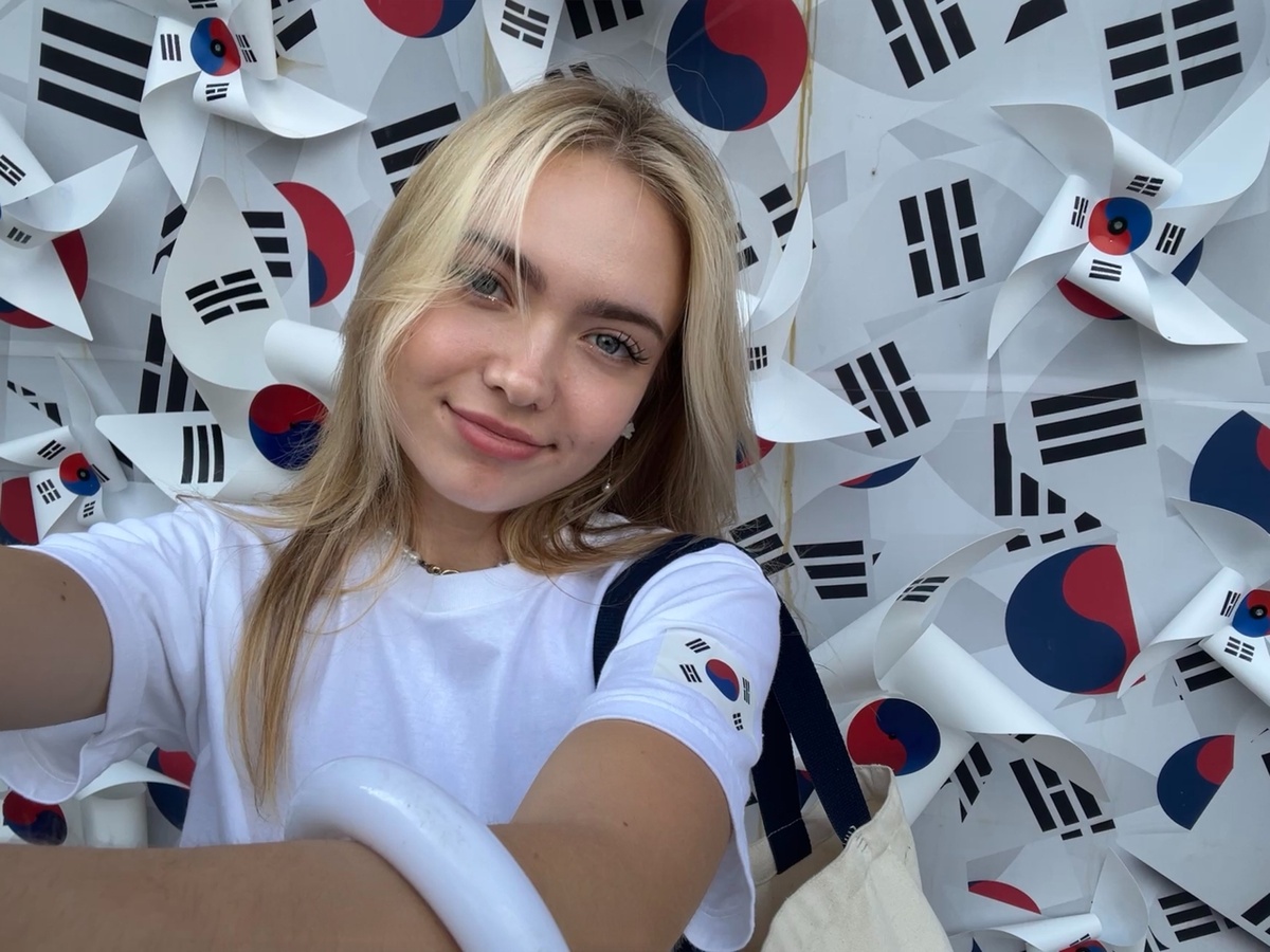 Эрика Скороход делает селфи на фоне стены, покрытой южнокорейскими флагами. (Эрика Скороход)