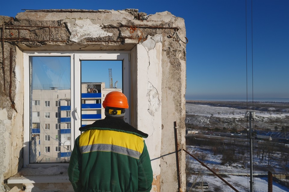    Строитель стоит на последнем сохранившемся этаже восстанавливаемой многоэтажки в Мариуполе Александр ИВАНОВ
