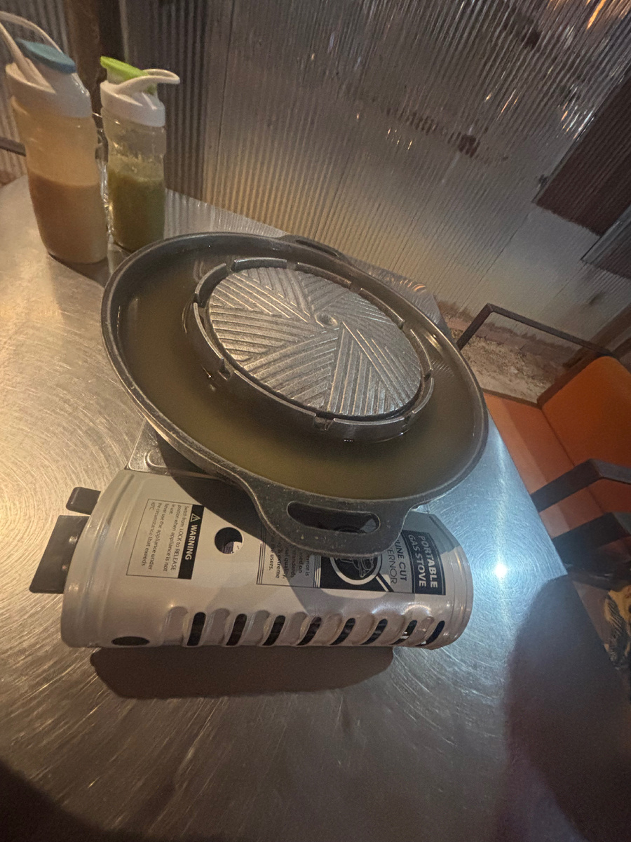 Необычный прибор на столе. В центре — купол для жарки мяса, по краям — бульон для овощей и лапши.