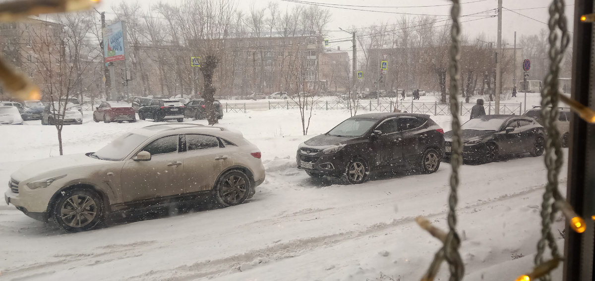 Красиво падает снег за окном кафе.