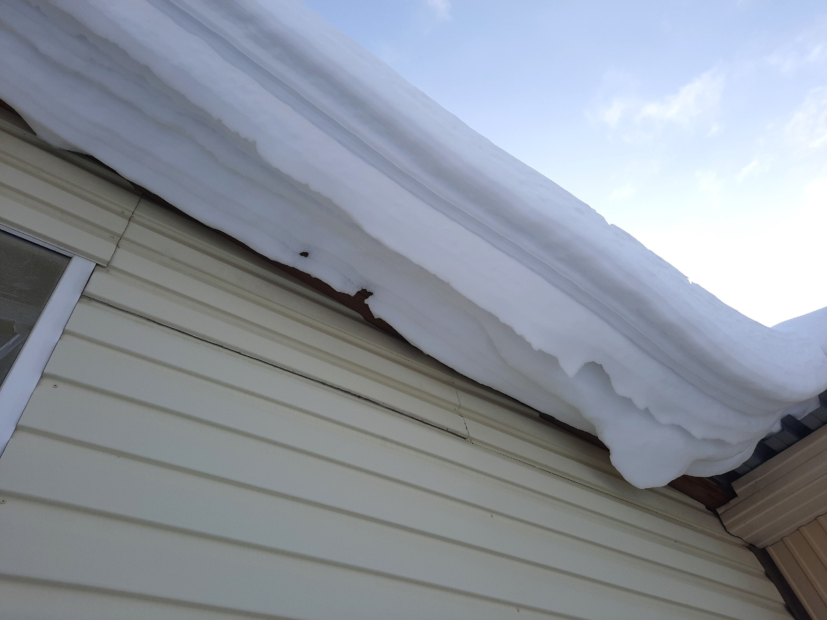 Шапка снега (снежный карниз), свисающая с крыши