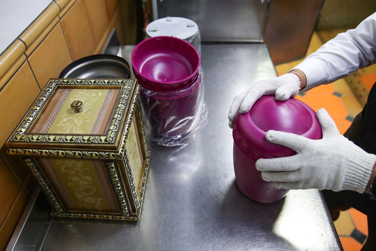  Оператор кремационного оборудования упаковывает урну с прахом в зале печей крематория. © Кирилл Кухмарь / ТАСС