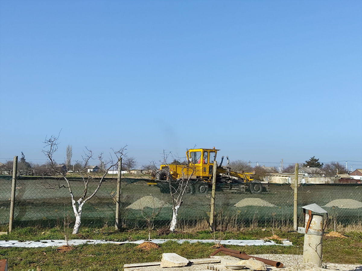 И грейдер прямо по траве шурует в начало дорожки.