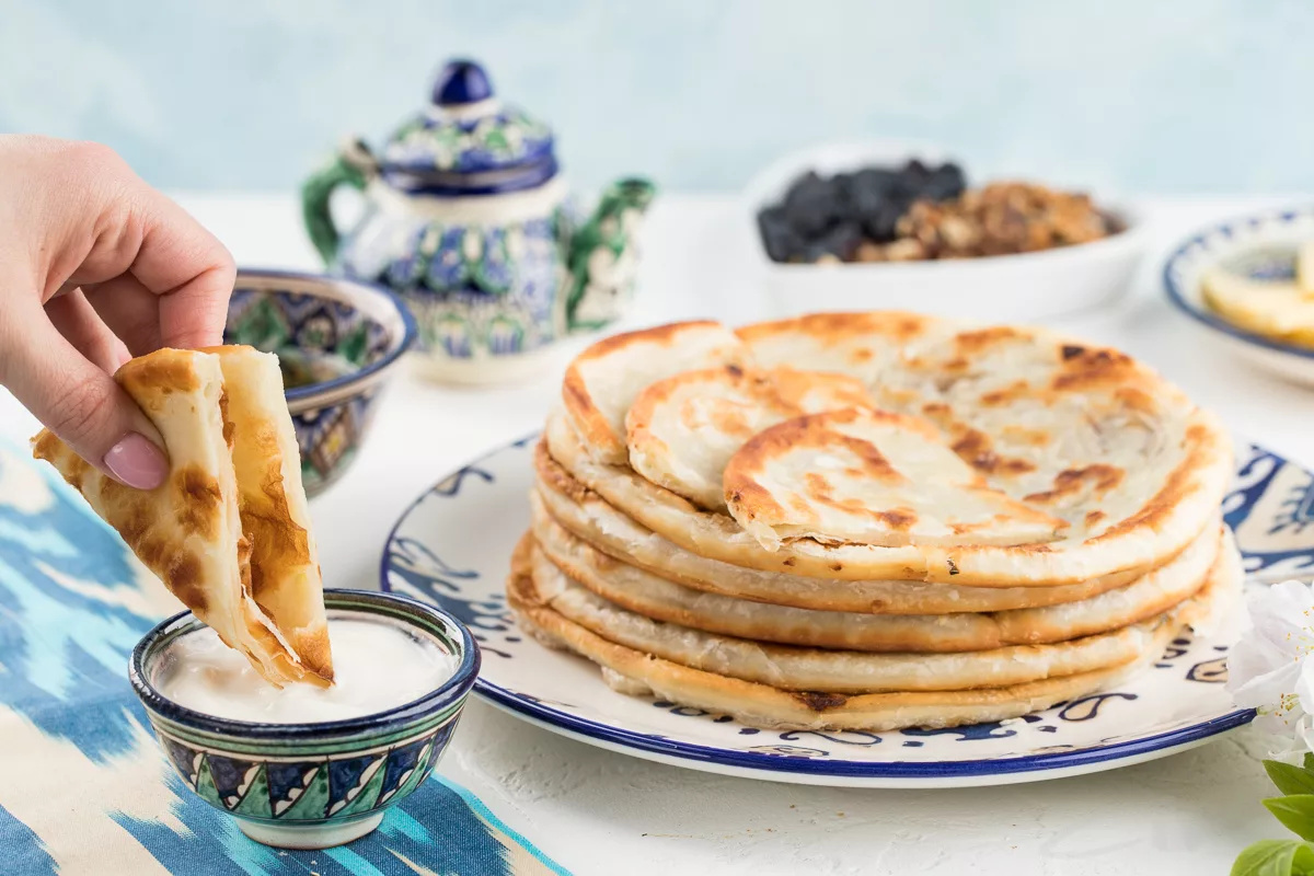    Название блюда происходит от тюркского слова «katlama». Корень kat означает «слой», глагол katlamak - «складывать». Аналоги этого блюда можно встретить по всему Великому шёлковому пути – от Турции до западного Китая.