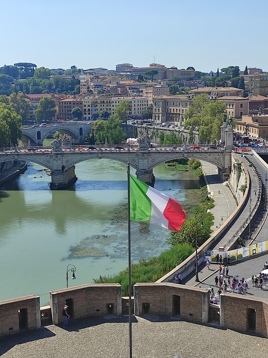 Просто красивый вид на Рим и Тибр с развевающимся итальянским флагом на вершине Замка Святого Ангела.