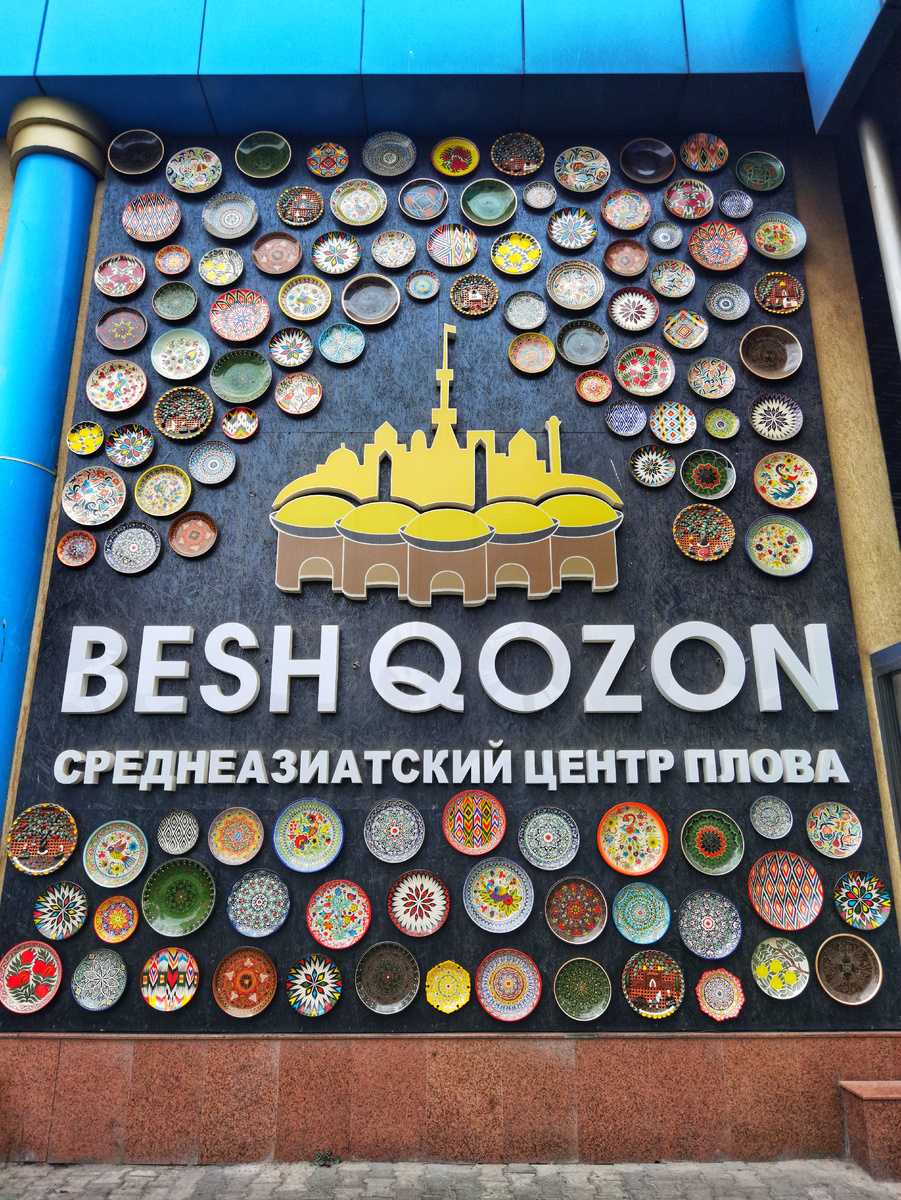 Стена, украшенная десятками расписных ляганов, встречает гостей как настоящий алтарь узбекской культуры и гостеприимства. Каждый узор на тарелке — это уникальная история, которая предвосхищает главное событие: дегустацию эталонного плова в самом сердце Средней Азии.