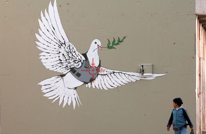    Мальчик рассматривает работу Бэнкси на рождественской выставке в городе Вифлеем на Западном берегу реки Иордан. 2 декабря 2007 года. Reuters/Ammar Awad