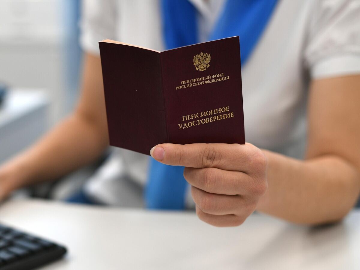    Сотрудник пенсионного фонда держит в руках пенсионное удостоверение | © РИА Новости / Максим Блинов