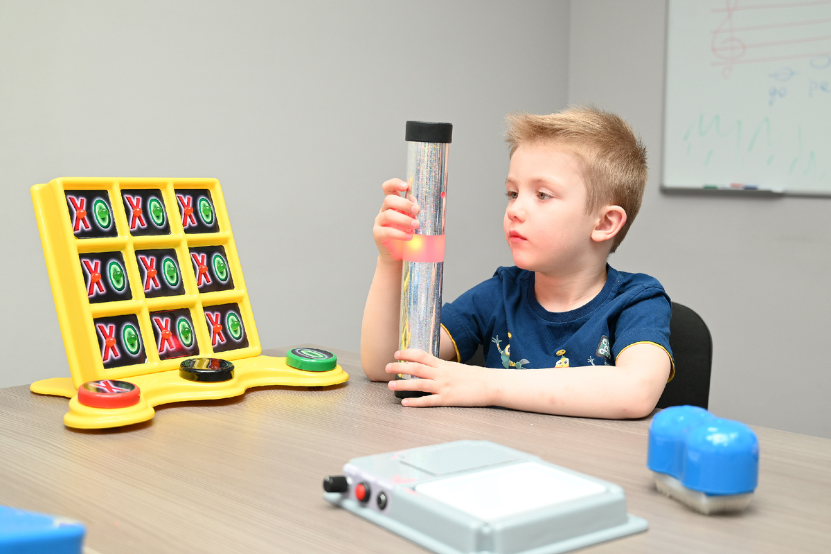 У ребенка в руках - сенсомоторная труба из набора для развития детей с аутизмом