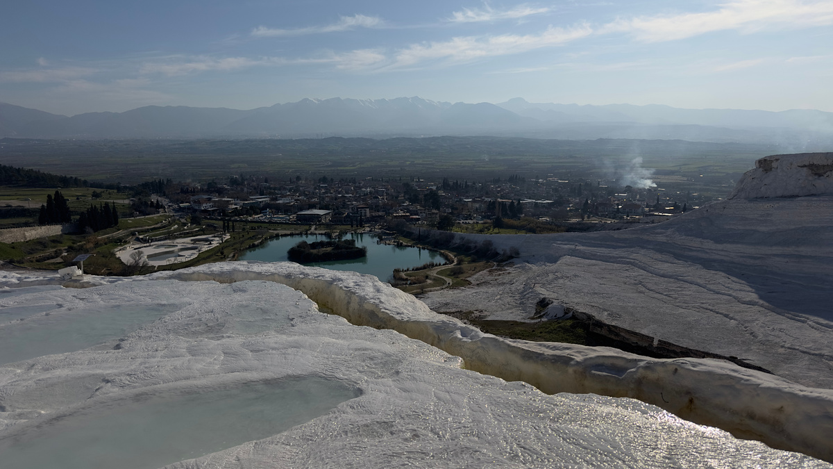 Вид с травертин на деревушку Памуккале и городок Денизли у подножия гор