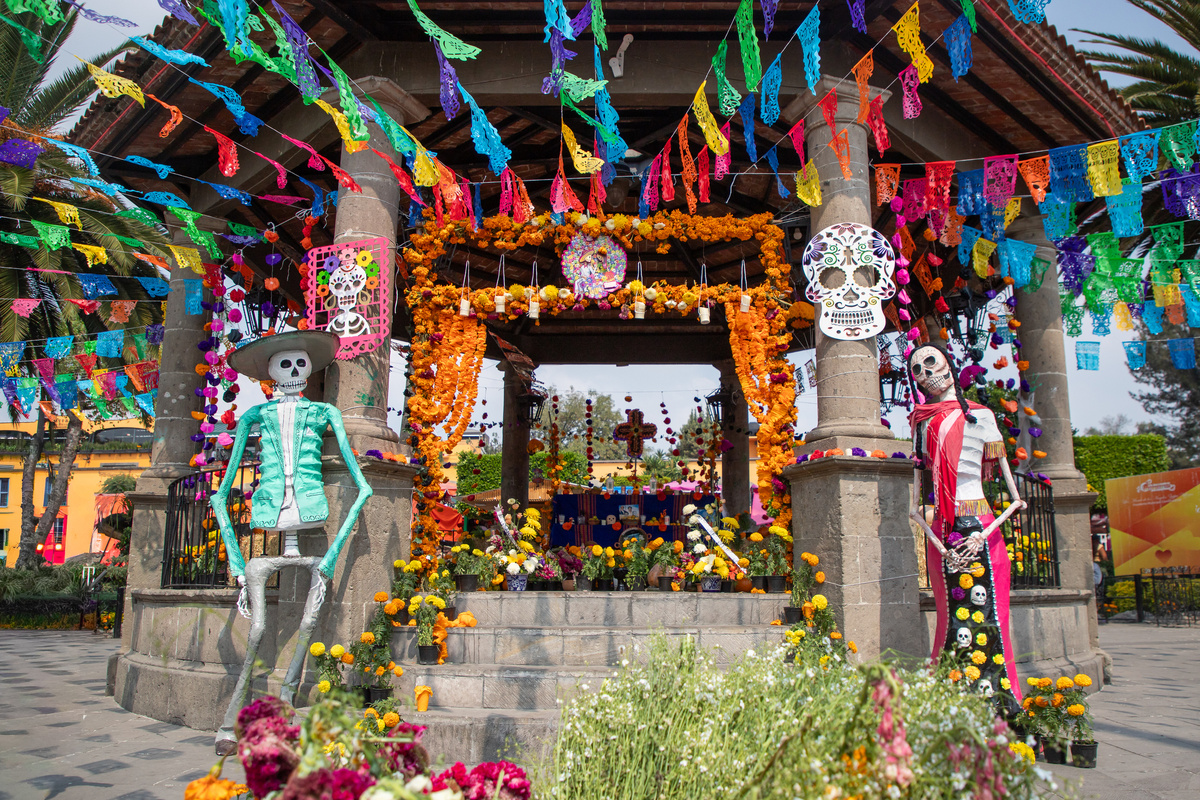 Площадь с алтарём, бумажными гирляндами и фигурами скелетов — традиционные символы мексиканского Дня мёртвых.