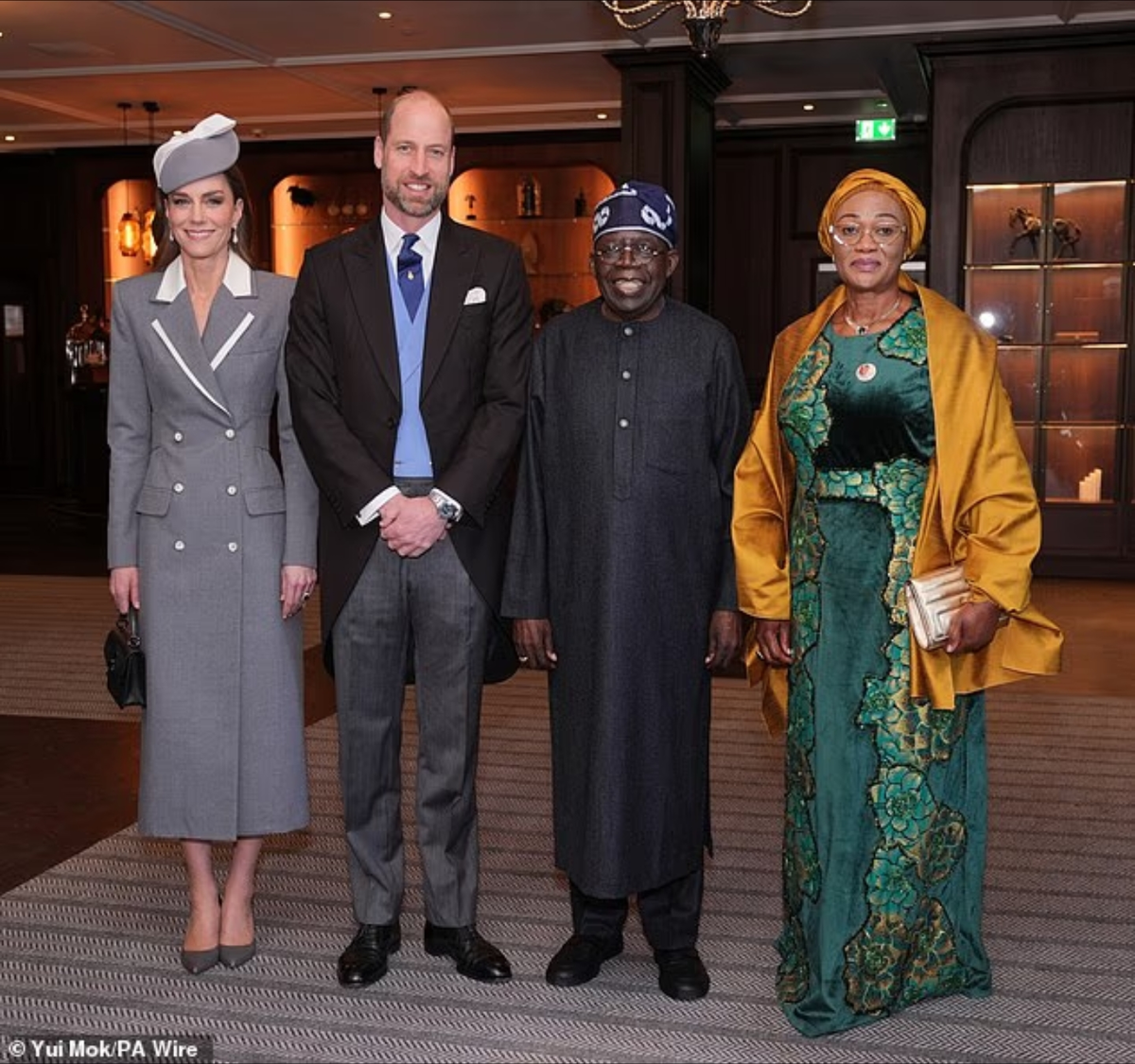 44-летняя Кейт переняла стиль своей свекрови, выбрав платье-пальто с контрастными лацканами цвета слоновой кости от Толу Кокер, восходящей звезды британско-нигерийского дизайна. На фотографии она запечатлена с принцем Уэльским, президентом Нигерии Болой Ахмедом Тинубу и первой леди Олуреми Тинубу.