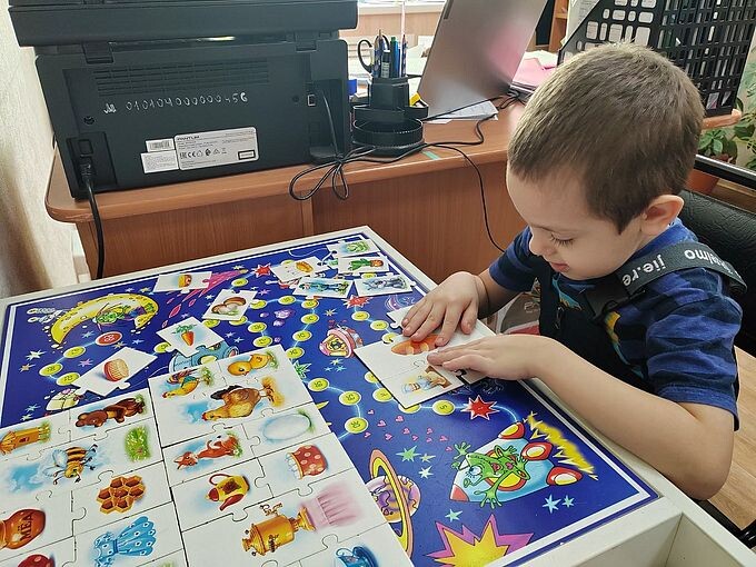 Мальчик за столом собирает пазлы