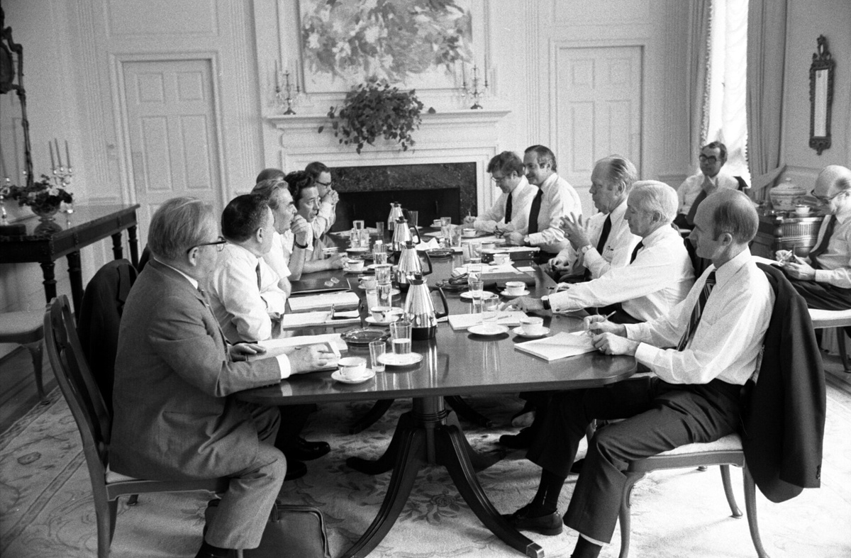 Президент Джеральд Форд встречается с генеральным секретарем ЦК КПСС Леонидом Брежневым в столовой американского посольства. (Среди американских участников встречи — Генри Киссинджер, посол США в СССР Уолтер Дж. Стоссел, заместитель советника по национальной безопасности Брент Скоукрофт, советник Госдепартамента Гельмут Зонненфельдт и т.д.