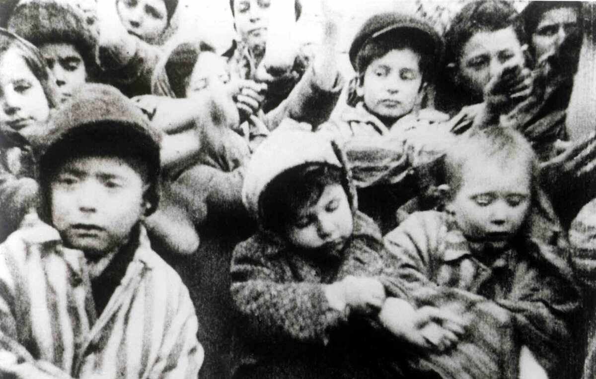 Дети, пережившие Освенцим, показывают свои руки с татуировками на фотографии из фильма об освобождении лагеря.