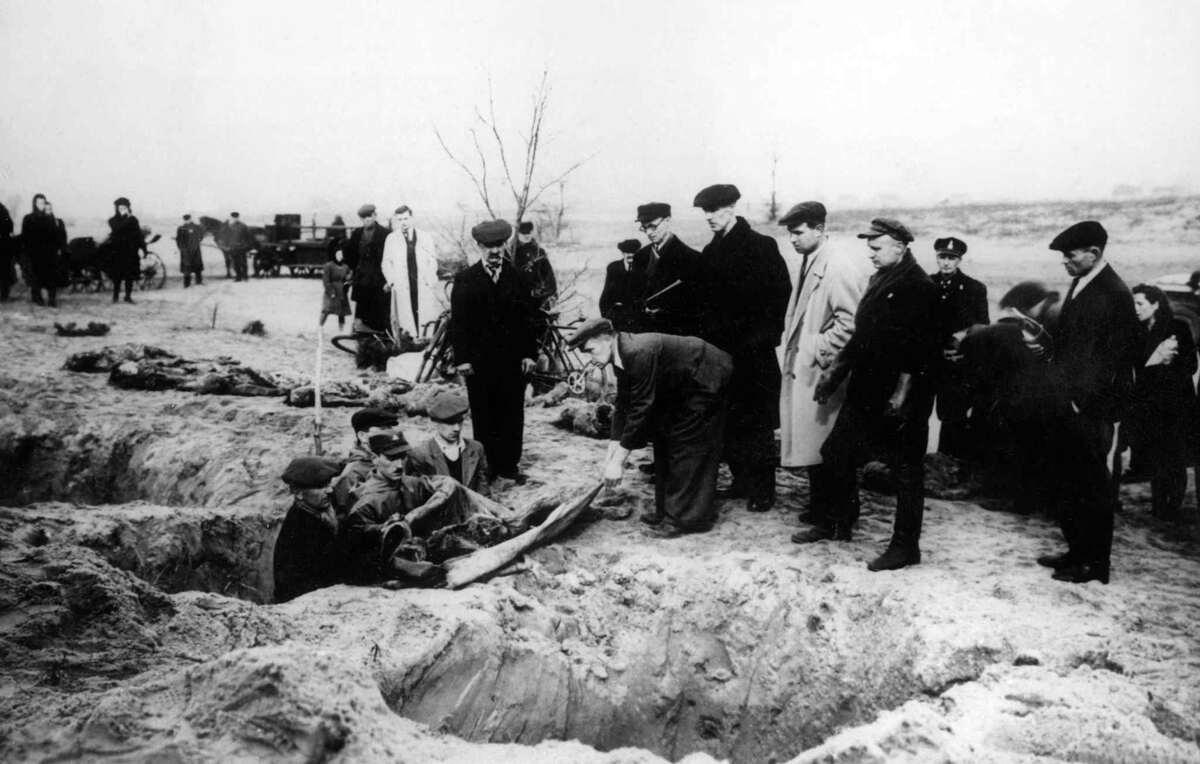 Гражданские лица и солдаты извлекают трупы из братских могил в концентрационном лагере Аушвиц-Биркенау в феврале 1945 года.