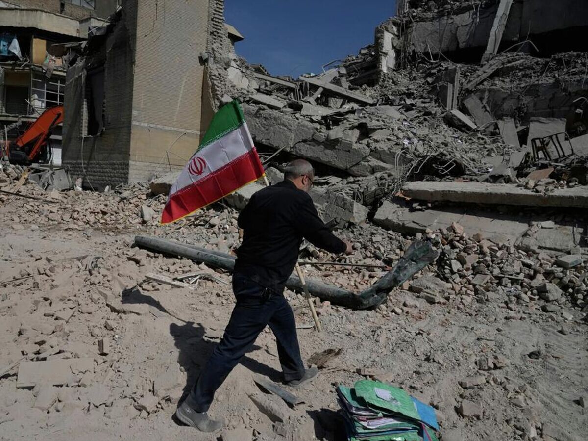    Мужчина с иранским флагом на месте удара в Тегеране | © AP Photo / Vahid Salemi