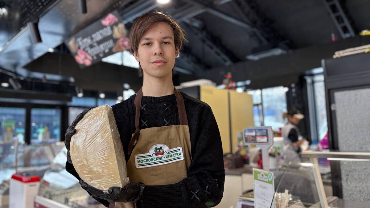    Продавец Марк Осин показывает один из крафтовых сортов сыра / Фото: Василиса Чернявская / Вечерняя Москва